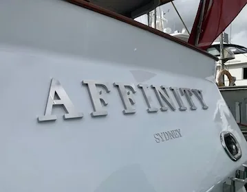 Brushed stainless lettering — restrained daytime presence with forgiving grain.